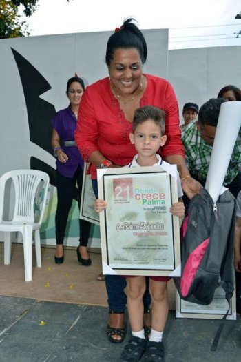 Mariulis Pérez Milán, funcionaria del Comité Provincial del Partido Comunista de Cuba (PCC), entrega premio de primer nivel al niño Raime Guevara Bello, de Camagüey.