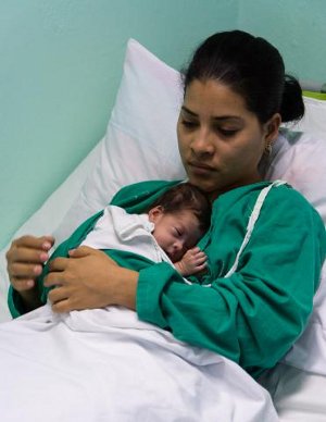 Las licenciadas en Enfermería Annely Boza y María de las Nieves Miranda, ayudan, como es común a la Dra. Eudelis Pons, médico de familia de Altagracia, quien se estrenó como madre de Emely Socarrás, una bebita que nació el 26 de enero, a las 29 semanas de gestación, con 1 414 gramos (3,1 libras), ya pesa 2 170 gramos, recibe la leche materna y como ha aumentado cuesta trabajo ponerla en el “saquito de canguro” creado para estos casos. Foto: Leandro Pérez Pérez