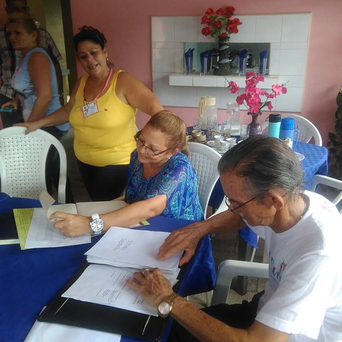 Parada junto a la mesa, Milagros Velazco Delgado, presidenta de la CEM. 