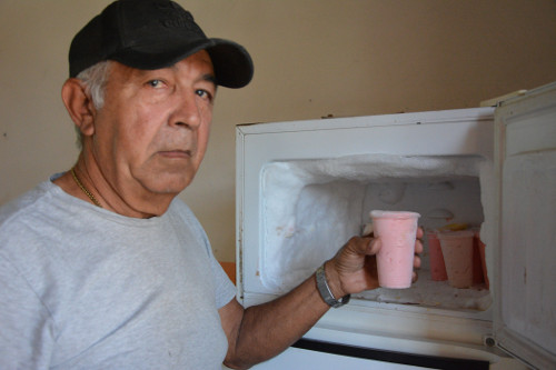 El jubilado cuentapropista muestra el refrigerador donde conserva los alimentos.