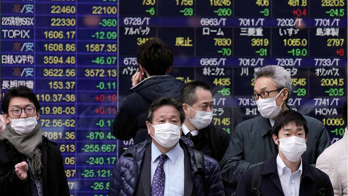 El coronavirus podría costar más de 300.000 millones a la economía mundial. En la foto, ciudadanos protegidos con mascarillas pasan frente a pantallas con información bursatil en Tokio. Foto: Tomada de elperiodico.com  Coronavirus, un freno para la economía mundial