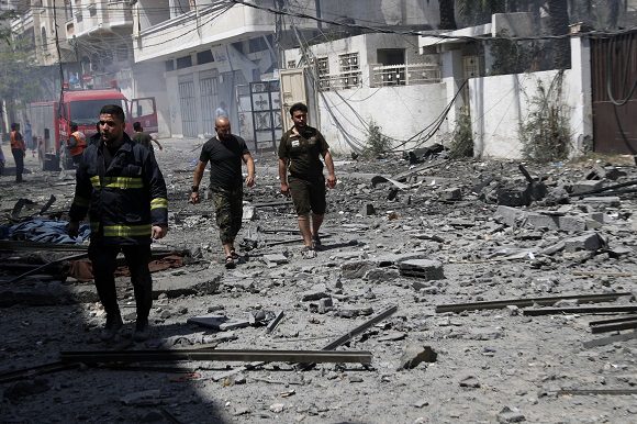 Unos bomberos inspeccionan una zona derruida por un bombardeo, este domingo en ciudad de Gaza. Foto: Adel Hana / AP